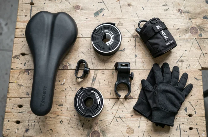 Vue à plat des cinq accessoires essentiels pour améliorer le confort du vélo Triban RC 120 sur un établi en bois