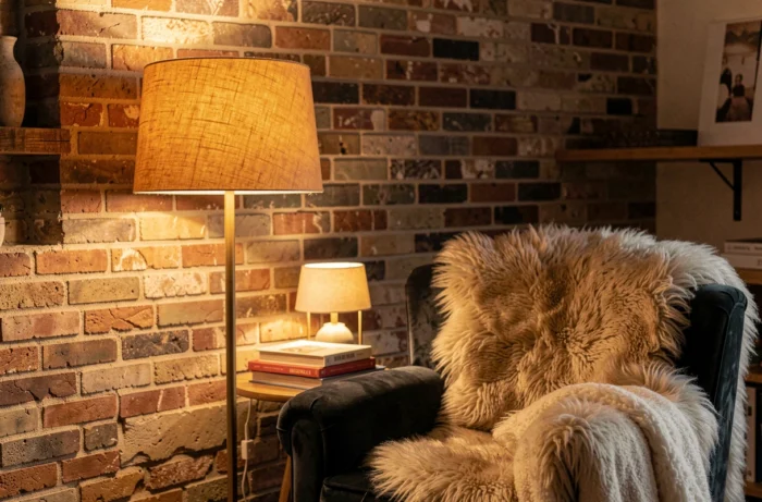 Éclairage indirect avec lampes d'appoint autour d'un fauteuil en velours dans un coin lecture cosy