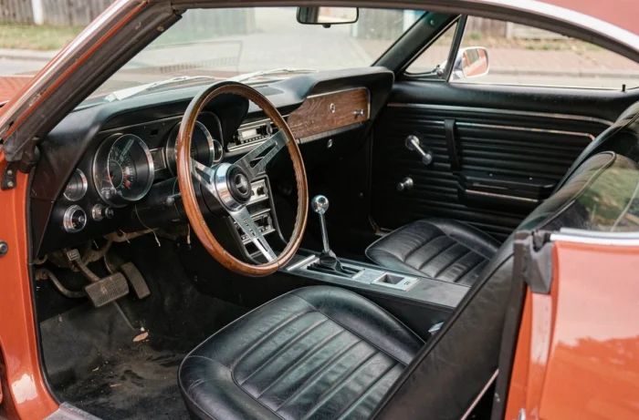 Intérieur cockpit de la Ford Shelby GT500 Eleanor avec tableau de bord vintage, volant bois et sièges baquet noirs en vinyle