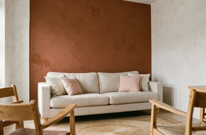 Mur d'accent peint en ton terracotta chaud dans un salon aux murs blancs avec canapé en lin