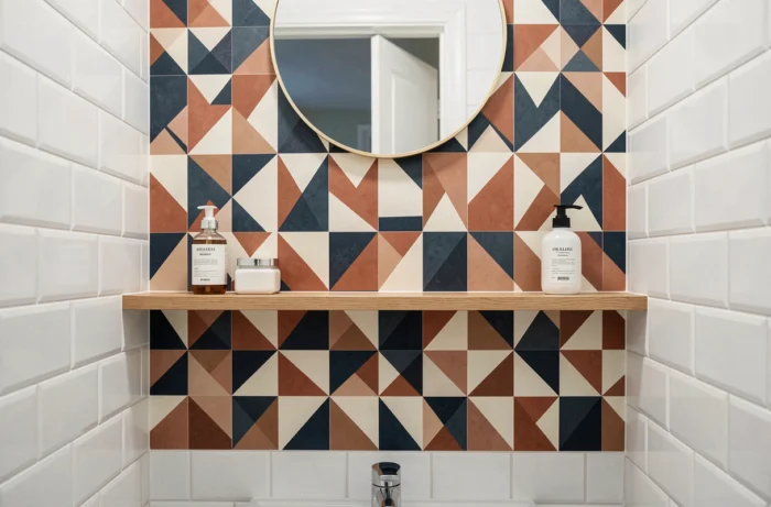 Papier peint adhésif géométrique appliqué sur une surface réduite entre deux étagères dans une petite salle de bain